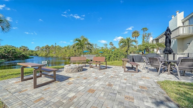 view of patio / terrace featuring a water view, an outdoor fire pit, and a balcony