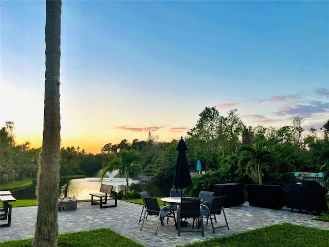 patio terrace at dusk featuring a water view