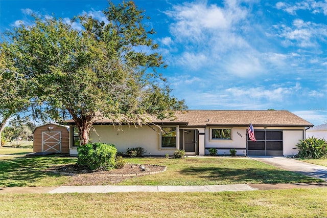 single story home featuring a storage shed, driveway, a front lawn, and stucco siding