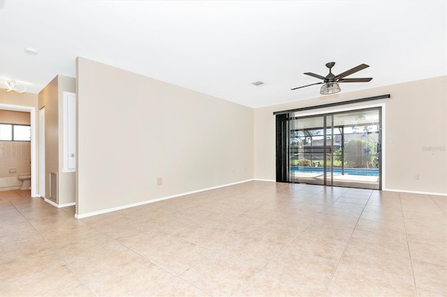 spare room with ceiling fan, light tile patterned floors, visible vents, and baseboards