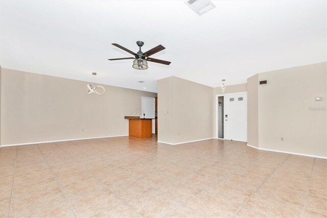 empty room with baseboards, light tile patterned floors, visible vents, and a ceiling fan