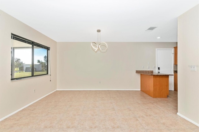 empty room with light tile patterned flooring, visible vents, baseboards, and an inviting chandelier