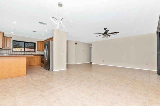 kitchen with stainless steel fridge, visible vents, open floor plan, and backsplash