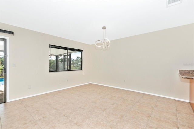 spare room with a chandelier, plenty of natural light, visible vents, and baseboards