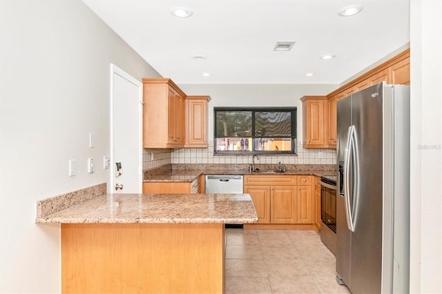 kitchen featuring stainless steel appliances, backsplash, a peninsula, and light stone counters