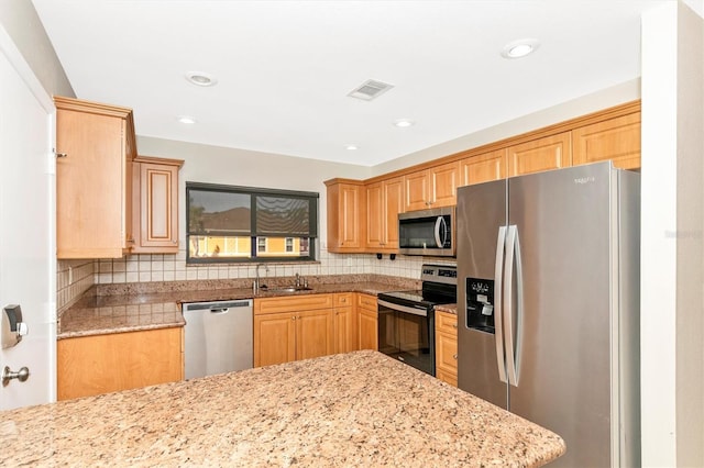 kitchen featuring stainless steel appliances, a sink, visible vents, backsplash, and light stone countertops