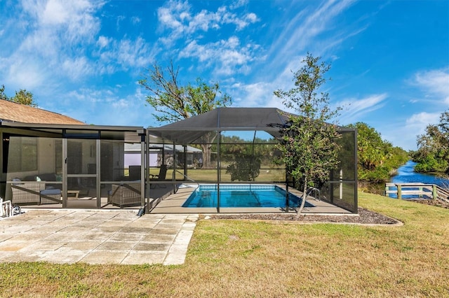 outdoor pool featuring glass enclosure, a lawn, and a patio