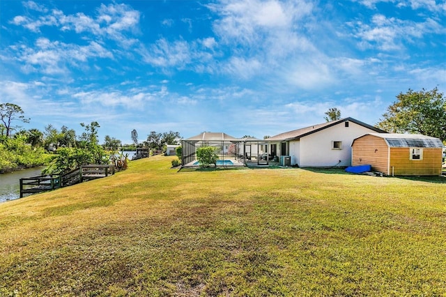 view of yard featuring an outbuilding, a lanai, a water view, and a storage shed