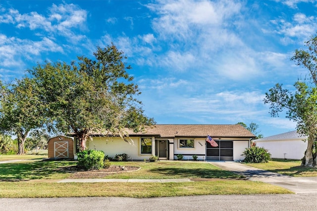 single story home with an outdoor structure, concrete driveway, stucco siding, a shed, and a front yard