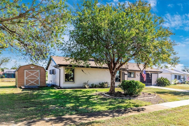 ranch-style home with a storage shed, a front lawn, an outbuilding, and stucco siding