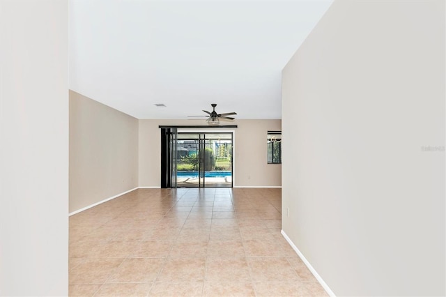 spare room with light tile patterned floors, a ceiling fan, and baseboards