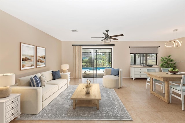 living room with a ceiling fan, visible vents, and light tile patterned floors