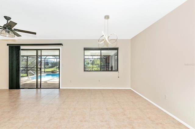 unfurnished room featuring light tile patterned floors, vaulted ceiling, baseboards, and ceiling fan with notable chandelier