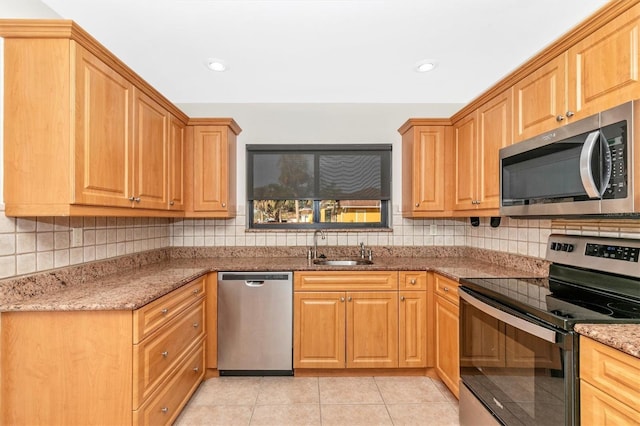 kitchen with appliances with stainless steel finishes, backsplash, a sink, and light stone countertops