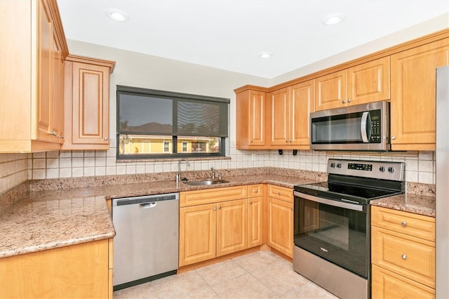 kitchen with light tile patterned flooring, stainless steel appliances, a sink, light stone countertops, and tasteful backsplash