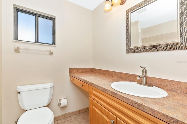 bathroom with toilet, vanity, and tile patterned floors