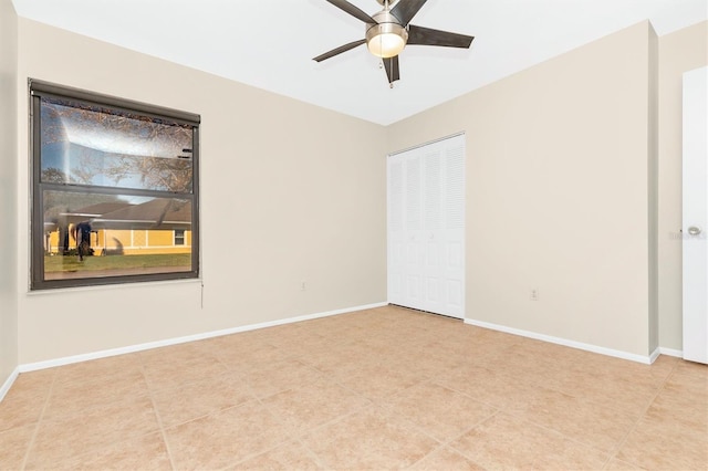 empty room with light tile patterned flooring, ceiling fan, and baseboards