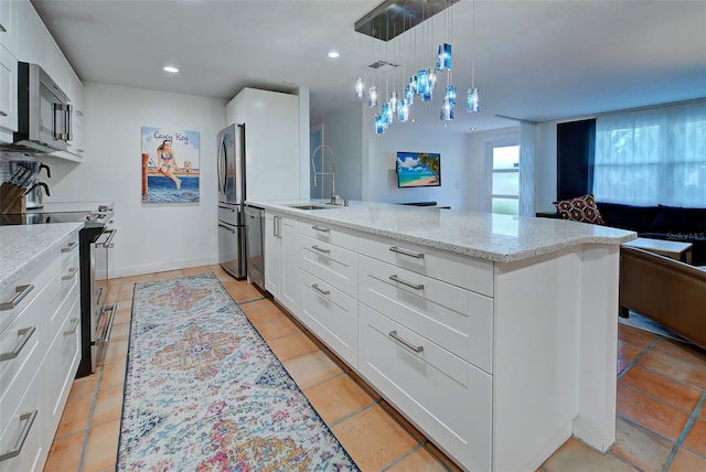 kitchen with a kitchen island with sink, sink, appliances with stainless steel finishes, decorative light fixtures, and white cabinetry