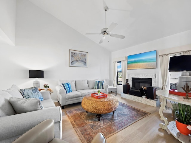 living room with a premium fireplace, ceiling fan, wood-type flooring, and high vaulted ceiling