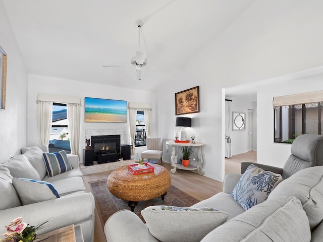 living room featuring ceiling fan, vaulted ceiling, light wood-type flooring, and a premium fireplace