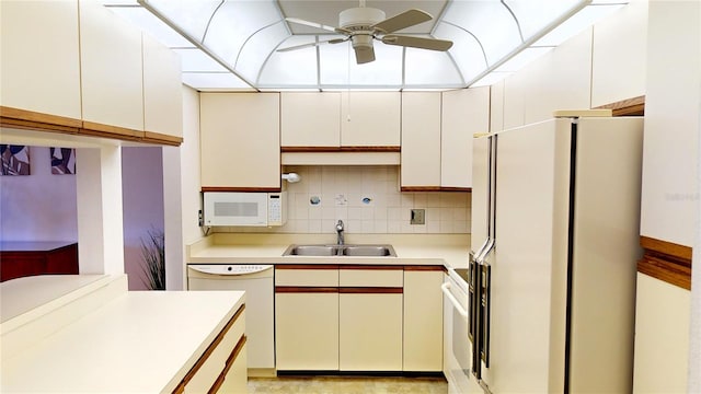 kitchen with white appliances, backsplash, sink, ceiling fan, and white cabinetry