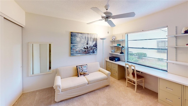 carpeted office featuring ceiling fan, built in desk, and a textured ceiling