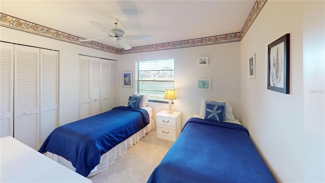 carpeted bedroom with ceiling fan and multiple closets