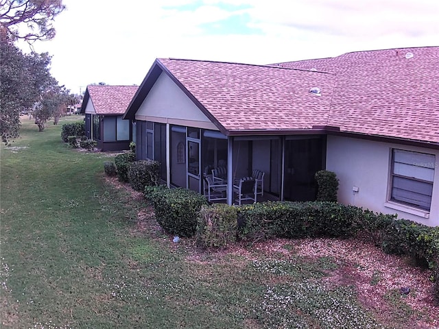 view of side of home with a sunroom and a yard