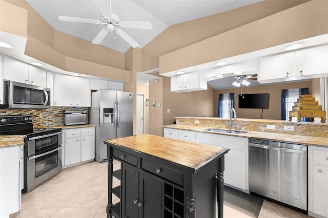 kitchen featuring lofted ceiling, sink, a kitchen island, white cabinetry, and stainless steel appliances