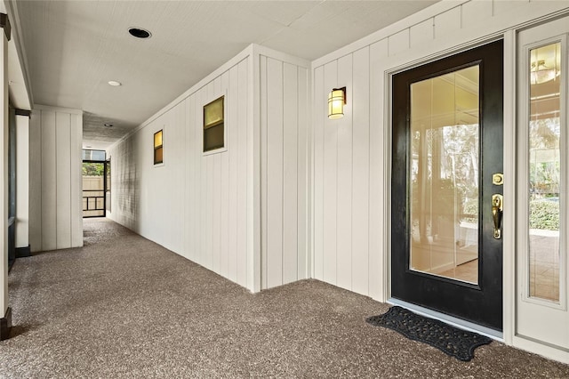 hall featuring carpet flooring and wooden walls