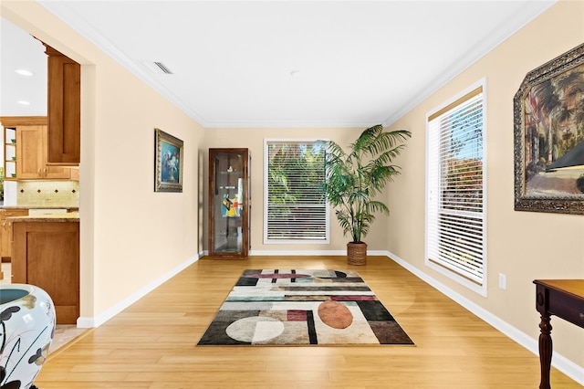 living area with light wood-type flooring and crown molding