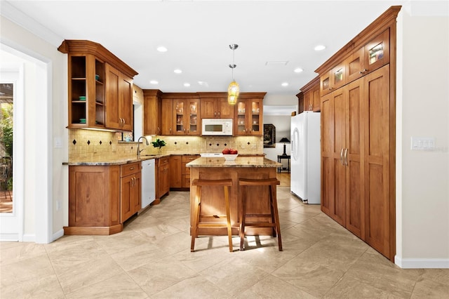 kitchen with light stone counters, a center island, pendant lighting, and white appliances