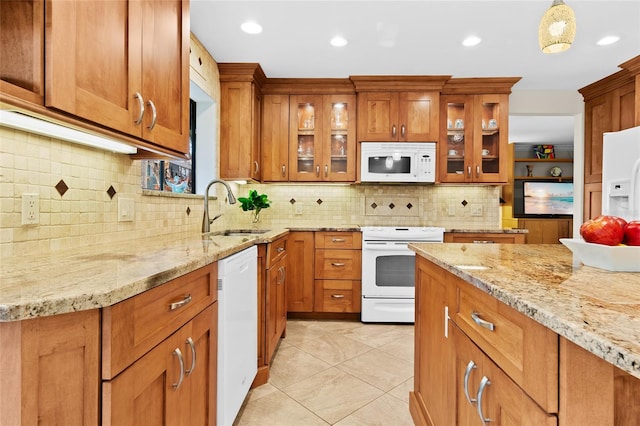 kitchen featuring light stone countertops, sink, hanging light fixtures, backsplash, and white appliances