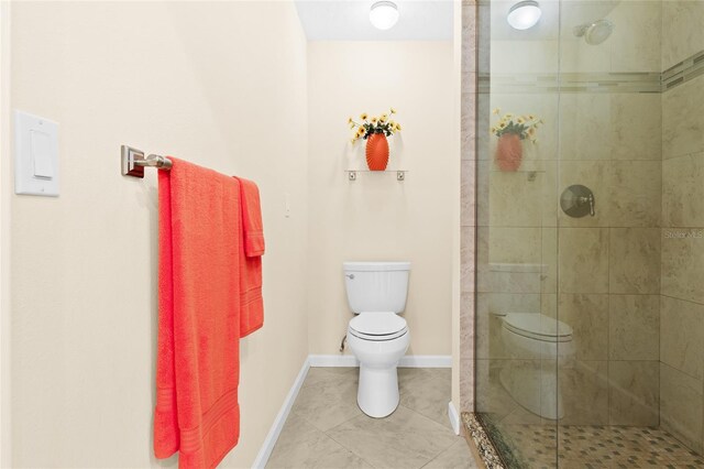 bathroom featuring tile patterned floors, toilet, and a tile shower