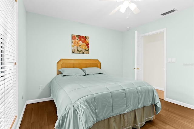 bedroom with multiple windows, ceiling fan, and hardwood / wood-style floors