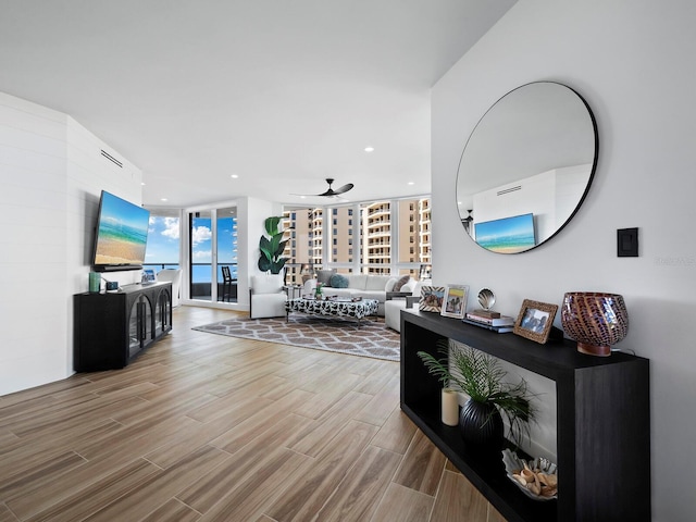 living room with hardwood / wood-style flooring, ceiling fan, and floor to ceiling windows