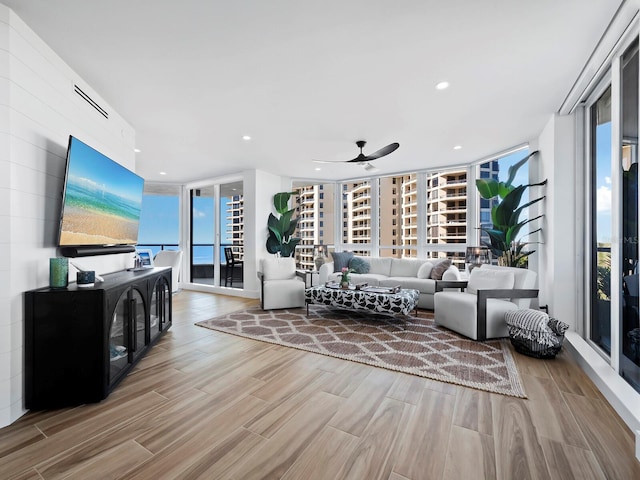 living room featuring hardwood / wood-style floors, ceiling fan, and a wall of windows