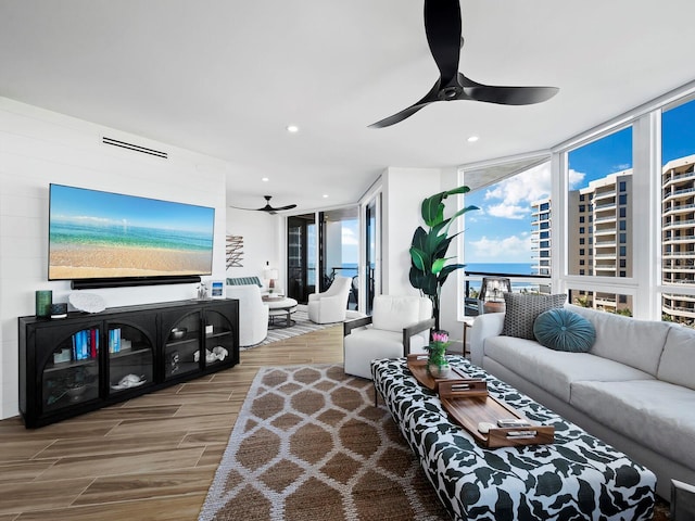 living room with ceiling fan, expansive windows, and wood-type flooring