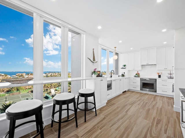 kitchen with white cabinets, pendant lighting, stainless steel appliances, and a healthy amount of sunlight