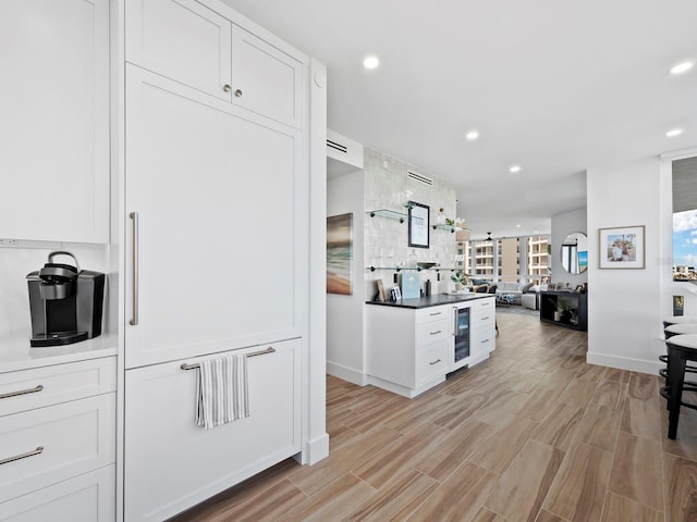 kitchen with light hardwood / wood-style floors, white cabinetry, beverage cooler, and tasteful backsplash