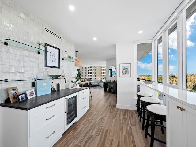 kitchen with a healthy amount of sunlight, white cabinets, and beverage cooler