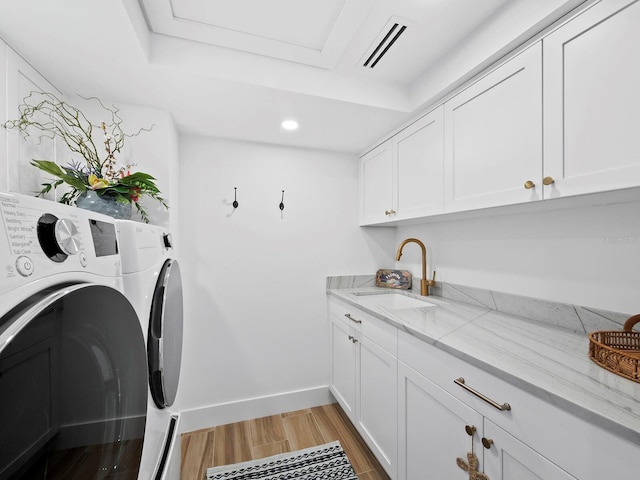 laundry area featuring cabinets, washing machine and dryer, light wood-type flooring, and sink