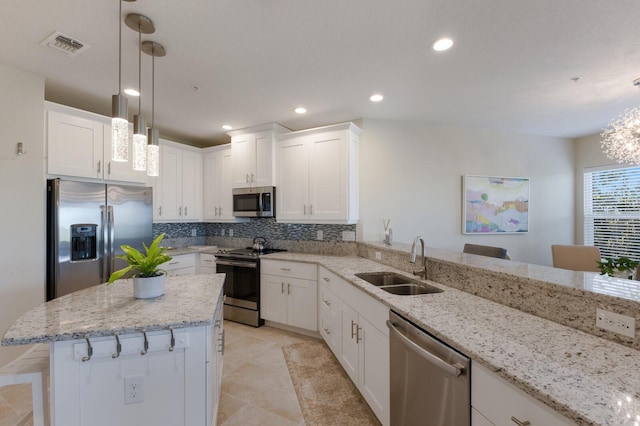 kitchen with appliances with stainless steel finishes, a breakfast bar, sink, pendant lighting, and white cabinetry