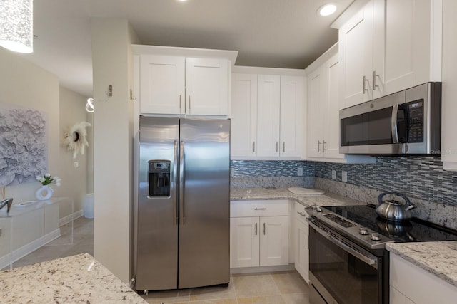 kitchen with decorative backsplash, light stone counters, white cabinets, and stainless steel appliances