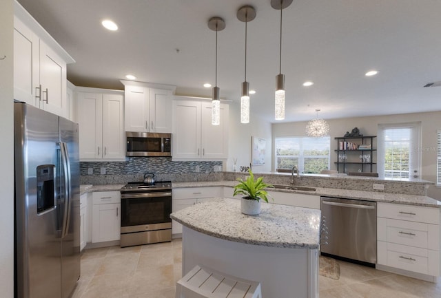 kitchen featuring kitchen peninsula, appliances with stainless steel finishes, sink, pendant lighting, and white cabinets