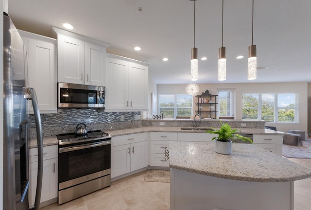 kitchen featuring sink, stainless steel appliances, kitchen peninsula, decorative light fixtures, and white cabinets