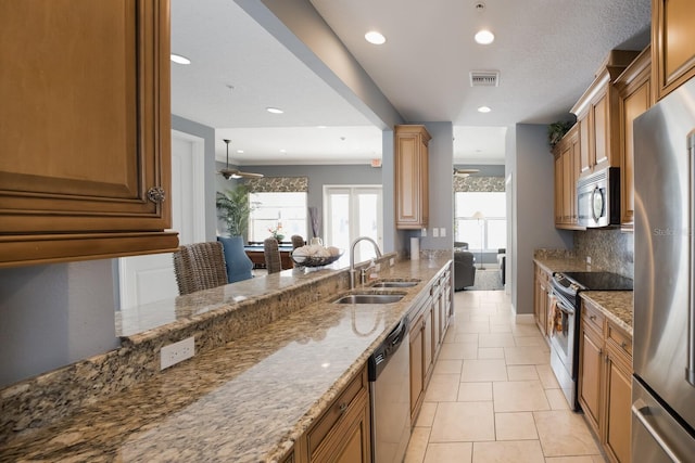 kitchen featuring ceiling fan, sink, light stone countertops, decorative backsplash, and appliances with stainless steel finishes