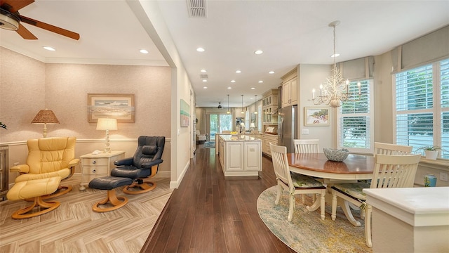 dining space featuring dark hardwood / wood-style flooring, a wealth of natural light, and ceiling fan with notable chandelier