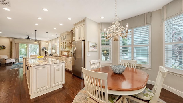 dining space with ceiling fan with notable chandelier, sink, and dark hardwood / wood-style floors