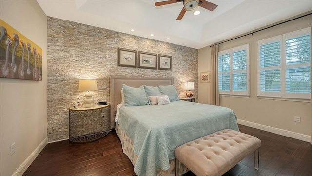 bedroom featuring ceiling fan, dark hardwood / wood-style floors, and a tray ceiling